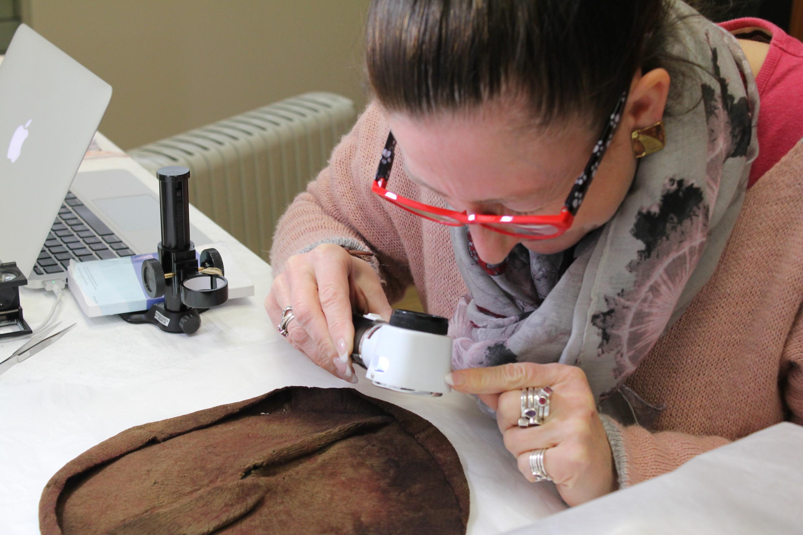 Jane performing an autopsy on a knitted cap lining at the V&A Museum